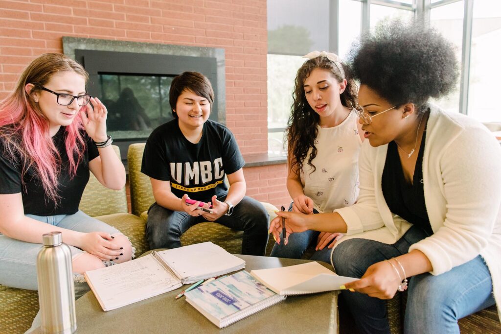 A diverse group of young women, sitting together studying.