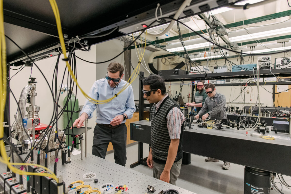 four people working in a quantum lab with colorful wires coursing all over